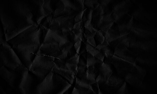 Dark black crumpled paper texture background with creased surface and shadows Background