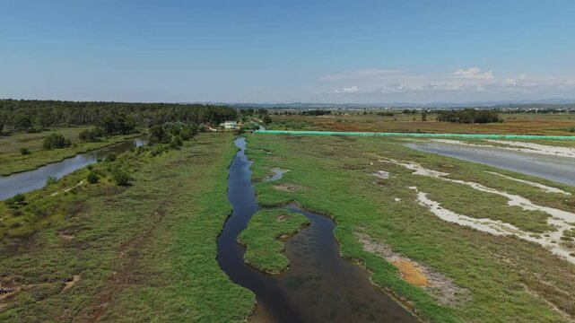 Aerial view of Karavasta Lagoon with winding water channels, marshland, and a small boat in Divjake, Fier County, Albania.