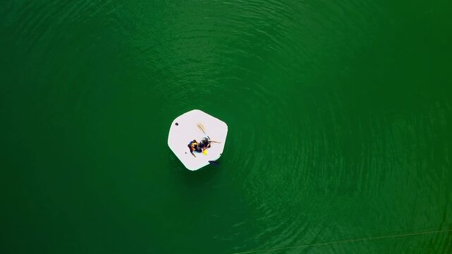 Aerial camera moving up. Kids playing and enjoying an inflatable boat in Kenyir Lake, Malaysia.