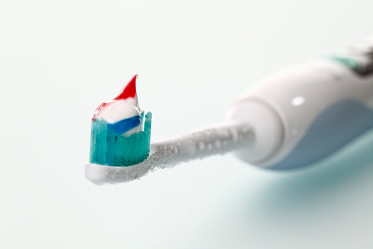 Electric toothbrush with toothpaste on white background
