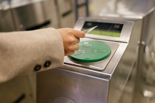 Woman scans card at subway turnstile indoors