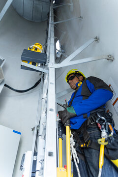 Male technician climbs a ladder inside a wind turbine tower