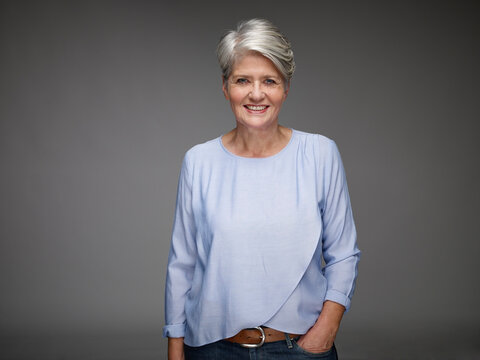Portrait of mature woman with grey hair in front of grey background