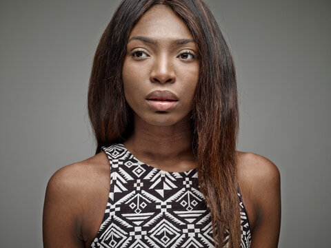 Portrait of pensive young woman in front of grey background