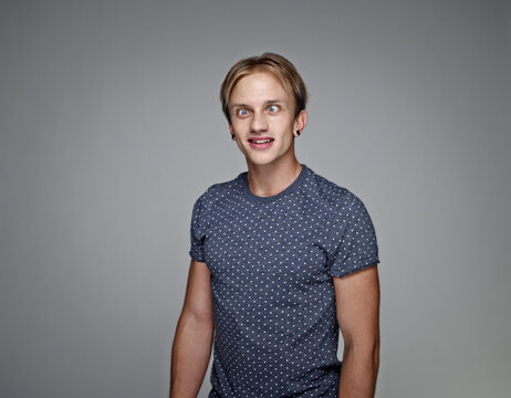 Portrait of cross-eyed young man in front of grey background