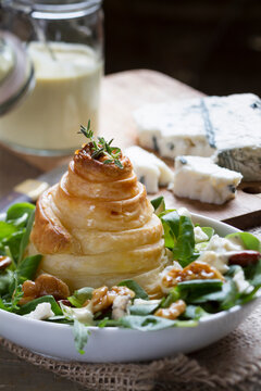 Pear in puff pastry on salad with gorgonzola cheese in background