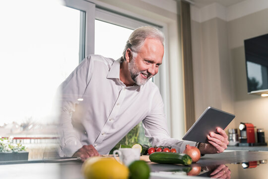 Smiling mature man using tablet in the kitchen