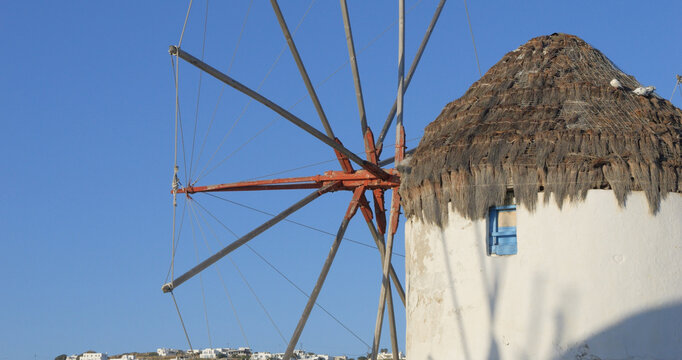 View of the iconic Mykonos windmill with its traditional thatched roof and wooden blades against a clear blue sky, Mykonos, Greece.