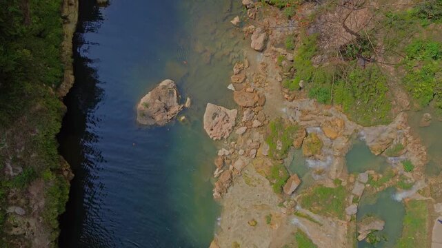 Aerial view of Sri Gethuk Waterfall with turquoise river pools, rocky cliffs, and lush vegetation in Yogyakarta, Special Region of Yogyakarta, Indonesia.
