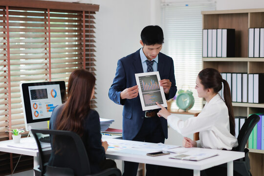 Business professionals analyzing marketing data and sales graphs during a corporate meeting, collaborating on financial strategy and discussing project performance in the office