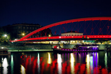 Fototapeta premium Horizontal night city photo of red illuminated bridge Ojca Bernatka reflected in river real life photography