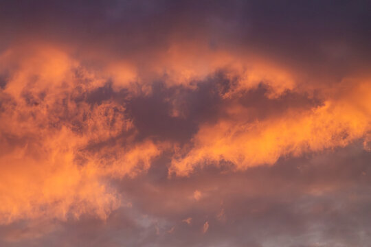 Horizontal close-up sunset cloudscape photo with warm orange clouds real life photography