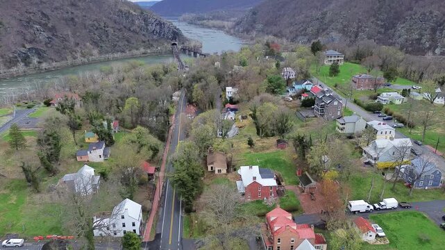 Historic tin roof residences border Washington Street approaching distant Potomac River water gap. Steep wooded bluffs enclose picturesque Appalachian town of Harpers Ferry, West Virginia