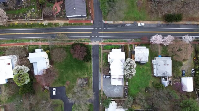 Neat paved roadway intersection crosses Washington Street between flowering spring dogwoods. Standing seam metal roofs crown historic residential lots in Harpers Ferry, West Virginia