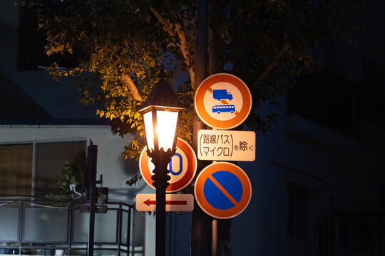 Panneaux routiers &eacute;clair&eacute;s par un lampadaire dans une rue nocturne