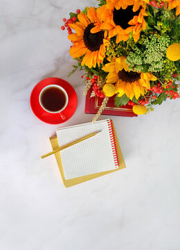 Empty notepad with pencil, tea cup, autumnal bouquet with sunflowers on marble table. Back to school, Education, beginning of the school year,  Knowledge Day, 1 September concept. copy space. top view