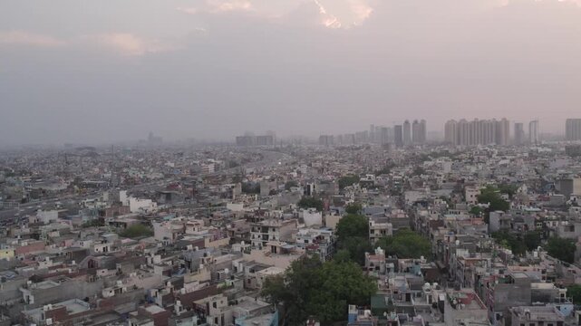 Aerial view of dense urban residential area with rooftops and distant high-rise buildings under a hazy sky in Ghaziabad, Uttar Pradesh, India.