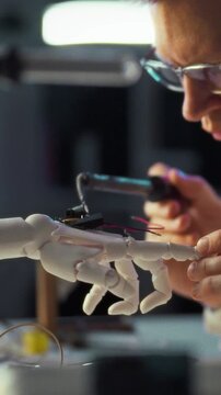 Inside a high-tech laboratory lined with electronic equipment, a researcher in a white lab coat adjusts a robotic hand linked by multiple wires, conducting science and robotics research concept