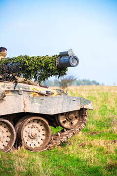 View of British Army armoured vehicle with camouflage netting on its cannon barrel, positioned on the grassy terrain of Salisbury Plain in Salisbury, Wilshire, United Kingdom.
