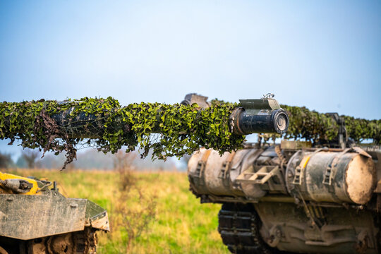 View of British Army armoured vehicles and tanks with camouflage netting on their barrels stationed on the grassy fields of Salisbury Plain in Salisbury, Wilshire, United Kingdom.