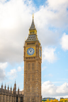 View of Big Ben and the Elizabeth Tower rising above the Palace of Westminster under a bright blue sky with scattered clouds in London, England, United Kingdom.