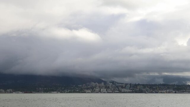 North Vancouver across the bay with dark rainy clouds above it, rain in Vancouver