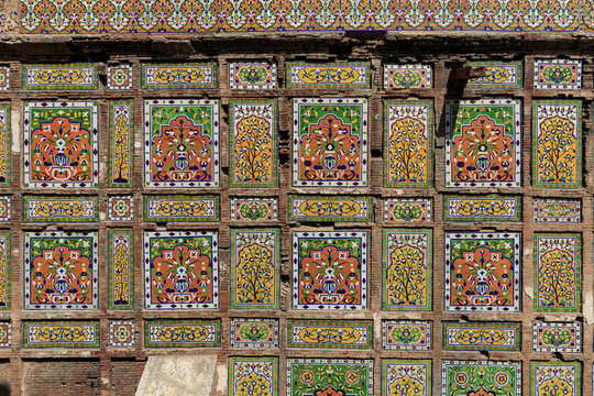 View of the intricate and colorful traditional Mughal-style glazed tilework on the historic Nawankot tomb, featuring floral motifs and geometric patterns in Lahore, Punjab, Pakistan.