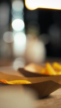 In a bustling kitchen, a chef serves golden French fries with tongs onto paper plates, amid fast-food prep stations and sizzling oil, displaying a quick service routine, fast food concept