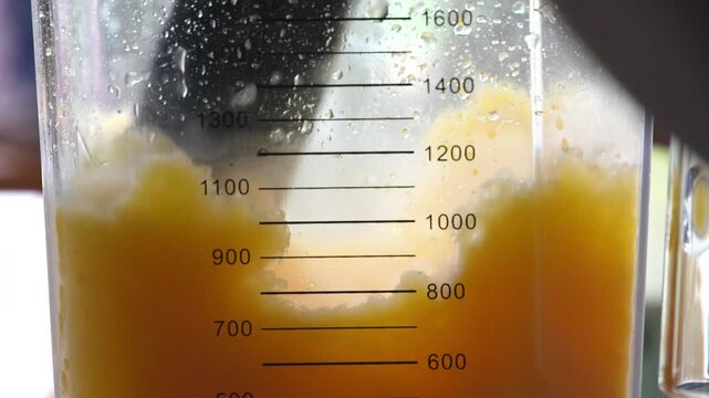 4K Close-up of yellow fruit smoothie blending in electric blender jar at cafe counter, healthy beverage, fresh mango smoothie, smoothie preparation and summer refreshment.