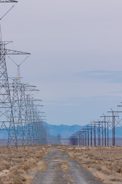 View of a long line of electrical transmission towers stretching across a vast desert landscape towards distant mountains in Nevada, United States.