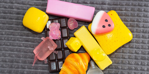 Colorful squishy toy assortment of candy shaped silicone pieces on textured mat for background and...