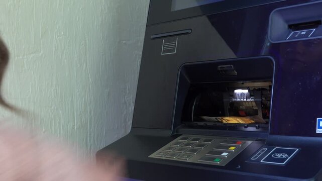 Woman withdrawing cash from an automated teller machine at bank branch.