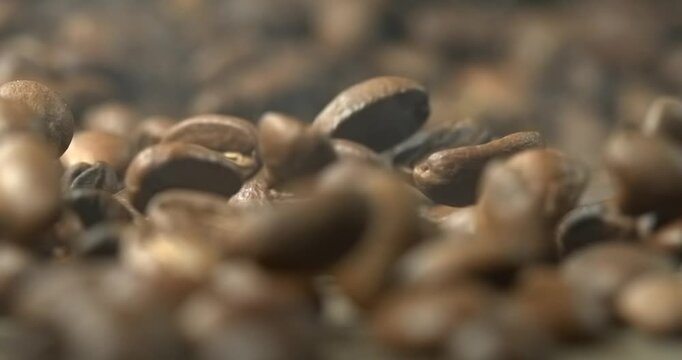 Roasted coffee beans bouncing across wooden table in super slow motion macro