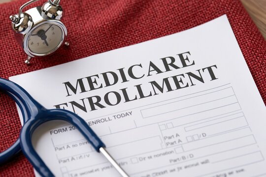 Close-up of a medicare enrollment form, stethoscope, and alarm clock on red textured surface