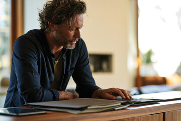 Obraz premium A stylish man examines fabric swatches in a bright, modern living space, illustrating creativity and personal style amid an inviting atmosphere filled with natural light.