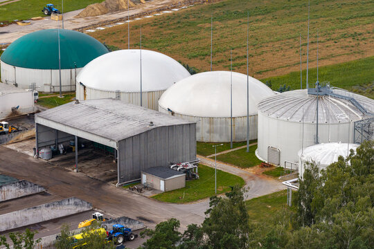 Aerial view of a large sugar plant processing sugar beets with dome-shaped storage tanks, industrial sheds, and agricultural fields in Poland.