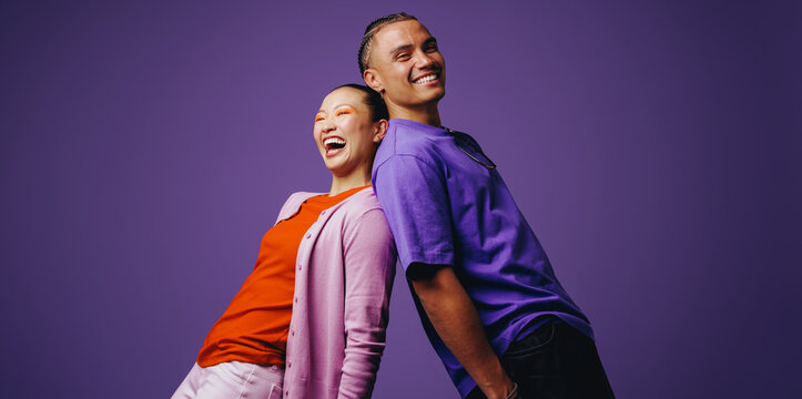 Smiling friends stand back to back in a vibrant studio setting