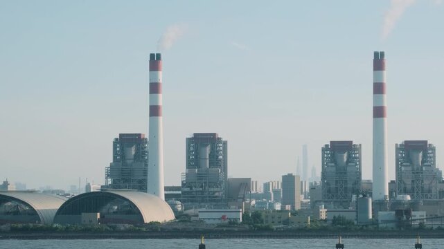 Thermal power station on Shanghai waterfront with industrial buildings, smokestacks and covered storage facilities. Energy infrastructure, heavy industry, electricity generation, industrial operations