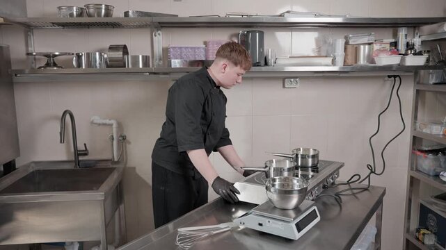Young male pastry chef turning on induction cooktop
