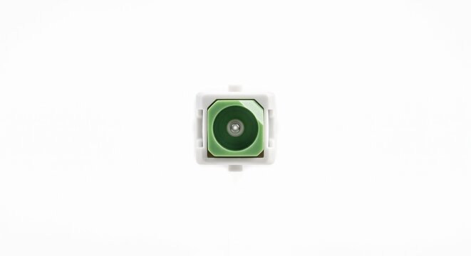 Extreme macro of a bare SC/APC fiber optic connector tip. Features an angled green ceramic ferrule and glass core. Telecommunications hardware on white.