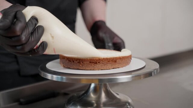Pastry chef piping cream on a sponge cake layer