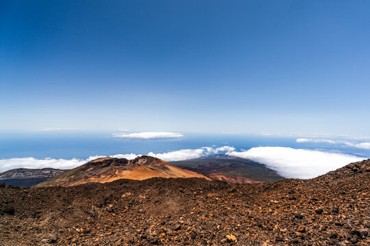 Santa Cruz de Tenerife, Spain - 28 June 2026: View of the volcanic landscape of Mount Teide with rugged rocky terrain, a sea of clouds below, and a clear blue sky.