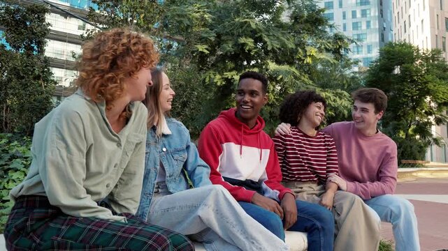 Diverse group of young friends laughing on a city bench