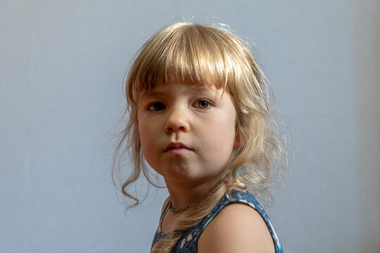 Thoughtful little blonde girl looking aside in close portrait indoors