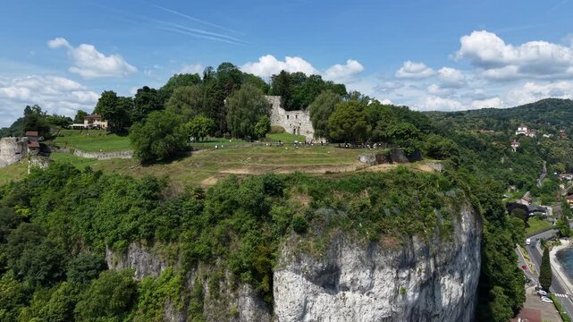 Rocca Borromeo di Arona Stands Atop A Cliff Overlooking Lake Maggiore In Arona, Piedmont, Italy. Aerial Pullback Shot