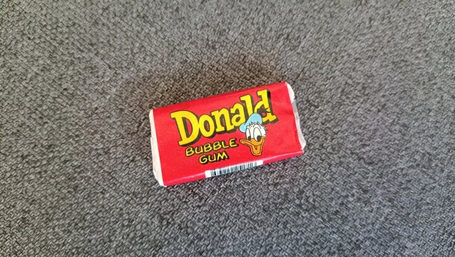 RIGA, LATVIA - AUGUST 19, 2026: Vintage Donald Duck bubble gum in red wrapper lying on a carpet. Classic 90s retro nostalgia and collector item.