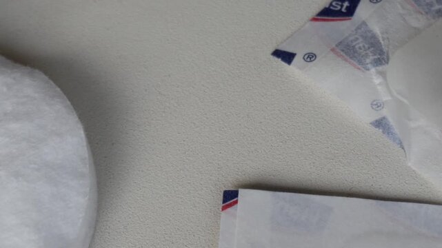 Panning medical products on white surface: strips, disinfectant, cotton pads.