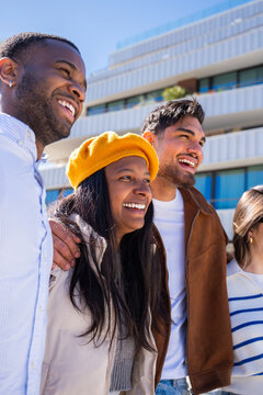 Vertical. Group of multicultural friends walk side by side through a bright residential district, enjoying friendship, sunshine and an easygoing urban lifestyle.