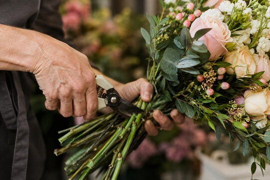 Skilled florist arranging fresh flowers and greenery into an elegant handmade bouquet in a flower shop