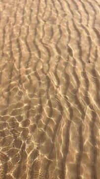 Clear water sand ripples texture beach background.Gold sand ripples under clear shallow water texture background.